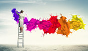 Young woman drawing splashes. Young woman standing on ladder drawing splashes with finger创意图片素材 - Ingram