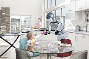 Robot feeding baby, mother in background创意图片素材 - Iconica