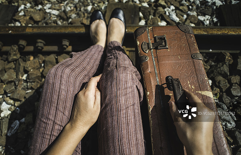 Woman and vintage suitcase on railway road