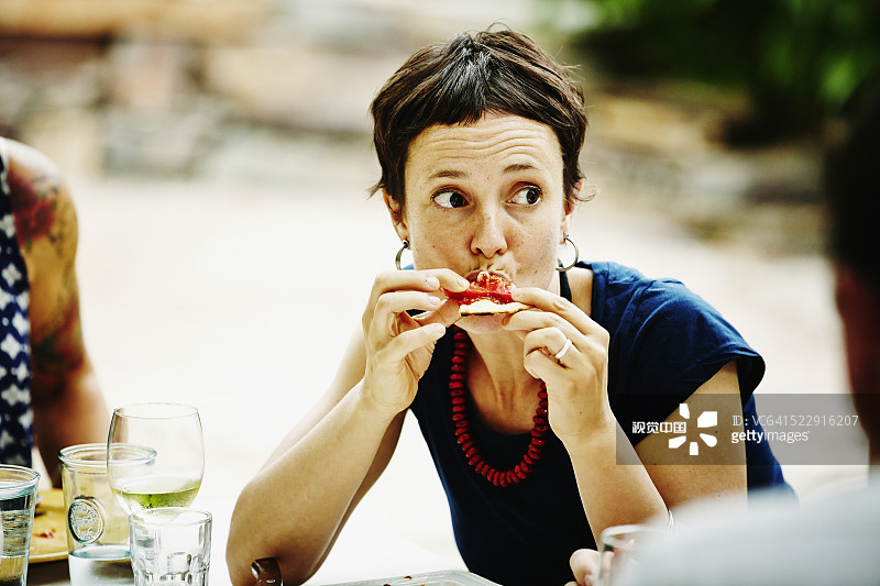 Woman taking bite of pizza during backyard dinner