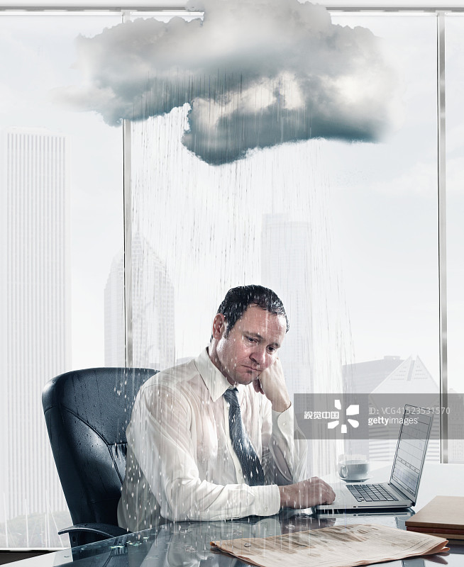 Rain falling on sad business man sitting at desk in office Rain falling on sad business man sitting at desk in office创意图片素材 - Corbis RM