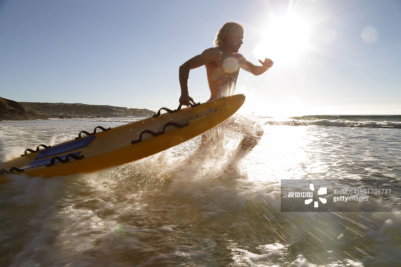 Lifeguard running into sea with rescue board