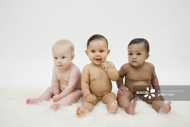Three naked babies sitting in a row