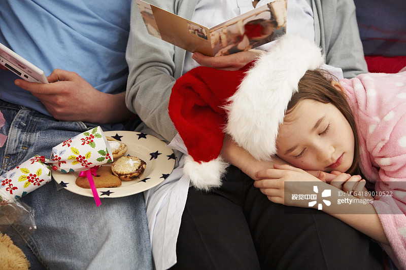 Girl sleeping on mother's lap on Christmas Girl sleeping on mother's lap on Christmas创意图片素材 - The Image Bank