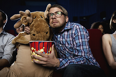 Man watching a movie with a toy moose corbis圖片素材