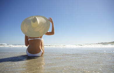 Woman Wearing Sun Hat Sitting on Beach corbis圖片素材