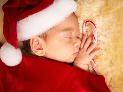 Sleeping newborn wearing Santa hat and holding candy cane gettyimages图片素材