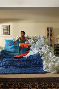 Boy (8-9) pretending to surf wave created from sheets on sofa gettyimages图片素材